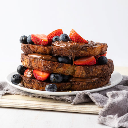 vegan french toast drizzled in crunchy chocolate spread with strawberries and blueberries